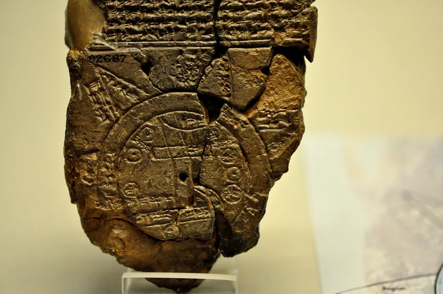 The broken clay tablet on a museum stand: rows of cuneiform above a circular map ringed by a band of ocean